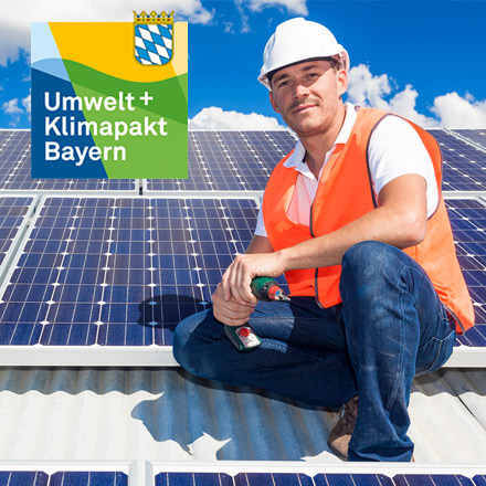 Techniker mit Bauhelm auf einem Dach mit Solarmodulen